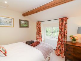 A bedroom with a bed and curtains at Magdalen Cottage in Hook Norton