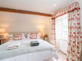 A bedroom with a bed and bedside table at Magdalen Cottage in Hook Norton