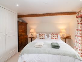 A bedroom with a bed, wardrobe, and chest of drawers at Magdalen Cottage in Hook Norton