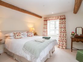 A bedroom with a double bed and a dresser at Magdalen Cottage in Hook Norton