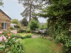 A garden with flowers, benches and a table at Magdalen Cottage in Hook Norton