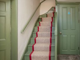 A staircase with a handrail and a door at Apartment 1, 86 Dyer Street Cirencester