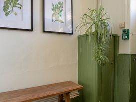 An entrance with a wooden bench and framed plant artwork at Apartment 1, 86 Dyer Street Cirencester