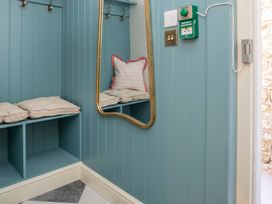 A hallway with a mirror, hooks, and cushions at Apartment 1, 86 Dyer Street Cirencester
