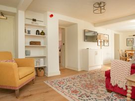 A living room with a sofa, armchair, and shelving at Apartment 1, 86 Dyer Street Cirencester