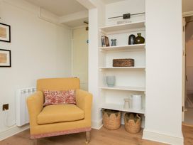 A living room with a chair and a shelf at Apartment 1, 86 Dyer Street, Cirencester