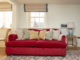 A living room with a red sofa and cushions at Apartment 1, 86 Dyer Street Cirencester