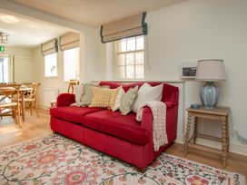 A living room with a red sofa and patterned rug at Apartment 1, 86 Dyer Street Cirencester