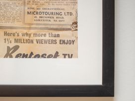 A newspaper advertisement for Rentaset TV framed in an indoor setting at Apartment 1, 86 Dyer Street, Cirencester
