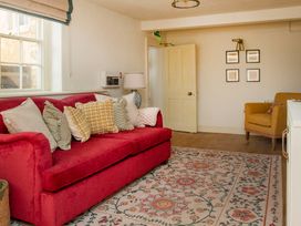 A living room with a red sofa and yellow chair at Apartment 1, 86 Dyer Street Cirencester