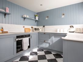 A kitchen with blue walls and modern appliances at Apartment 1, 86 Dyer Street in Cirencester