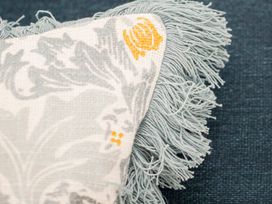 A close-up of a decorative cushion with fringes at Apartment 1, 86 Dyer Street in Cirencester