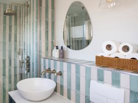 A bathroom with a shower, washbasin, and toiletries at Apartment 1, 86 Dyer Street Cirencester