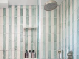A bathroom with a shower and tiled walls at Apartment 1, 86 Dyer Street Cirencester
