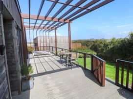 An outdoor deck area with seating and a view at Lodge 83, Gwel an Mor Portreath