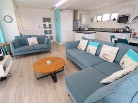 A living room with a blue sofa and a coffee table at Lodge 83, Gwel an Mor, Portreath