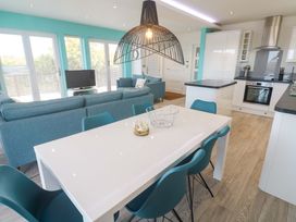 A living room with a sofa, dining table, and kitchen area at Lodge 83, Gwel an Mor in Portreath