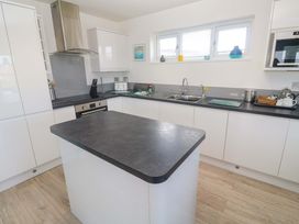 A kitchen with an island, sink, and cooking stove at Lodge 83, Gwel an Mor in Portreath