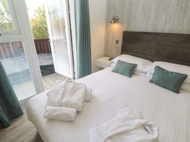 A bedroom with a bed and sliding door leading to a deck at Lodge 83, Gwel an Mor in Portreath