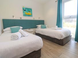A bedroom with two beds and a painting at Lodge 83, Gwel an Mor in Portreath