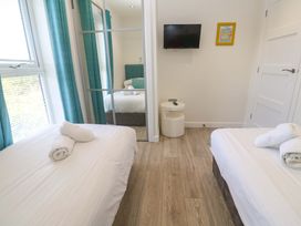 A bedroom with twin beds and a television at Lodge 83, Gwel an Mor, Portreath