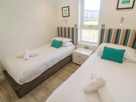 A bedroom with two single beds and a bedside table at Lodge 83, Gwel an Mor in Portreath