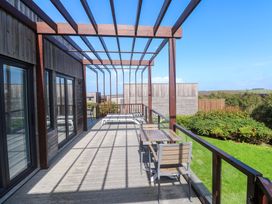 An outdoor area with a wooden deck and table at Lodge 83, Gwel an Mor in Portreath