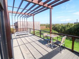 An outdoor area with a table and chairs under a pergola at Lodge 83, Gwel an Mor in Portreath