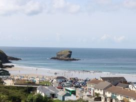 A beach scene with a rock formation and buildings at Lodge 83, Gwel an Mor in Portreath