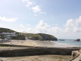 A beach with people and houses on the cliff at Lodge 83, Gwel an Mor, Portreath