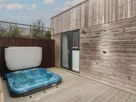 An outdoor area with a hot tub and wooden walls at Lodge 83, Gwel an Mor in Portreath