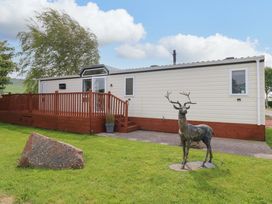 A mobile home with a deck and a statue of a deer at Plot 12 in Carlisle