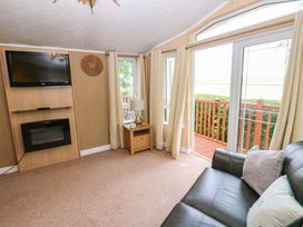 A living room with a television, fireplace, and sofa at Plot 12 in Carlisle