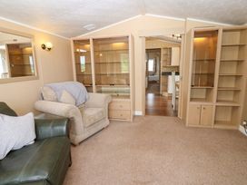 A living room with a sofa and shelving units at Plot 12 in Carlisle