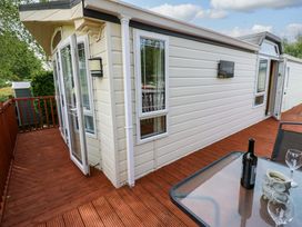 A deck area with a table and wine bottle at Plot 12 in Carlisle