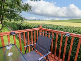 A patio with a glass and chair overlooking a field at Plot 12 in Carlisle