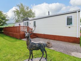 A mobile home with decking and a deer statue at Plot 12 in Carlisle