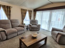 A living room with a table and seating at Fernwood Lodge in Fritton near Belton, Norfolk