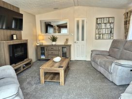 A living room with a television and sofa at Fernwood Lodge in Fritton near Belton, Norfolk