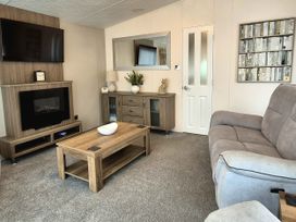 A living room with a television and coffee table at Fernwood Lodge in Fritton near Belton, Norfolk