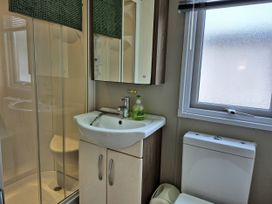 A bathroom with a shower, sink, and toilet at Fernwood Lodge, Fritton near Belton, Norfolk