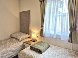 A bedroom with two single beds and a lamp at Fernwood Lodge in Fritton near Belton, Norfolk