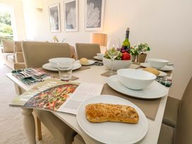 A dining table set with plates, glasses, and a fruit bowl at Apartment 11 in Poole