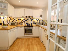 A kitchen with various appliances and yellow blue tiled backsplash at Apartment 11 in Poole