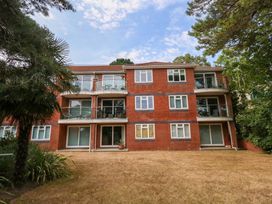 A building with balconies and windows surrounded by grass and trees at Apartment 11 in Poole