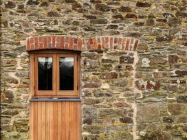 A window and wooden door on a stone wall at Lower Walreddon Farm Tavistock