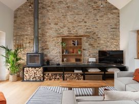 A living room with a stone wall and fireplace at Lower Walreddon Farm in Tavistock