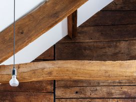 A ceiling view with wooden beams and a light bulb at Lower Walreddon Farm in Tavistock
