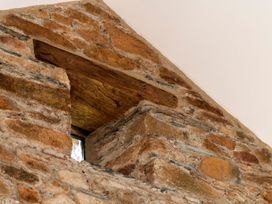A stone wall with a wooden beam and a window opening at Lower Walreddon Farm, Tavistock
