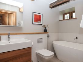 A bathroom with a bathtub, toilet, sink, and mirror at Lower Walreddon Farm Tavistock